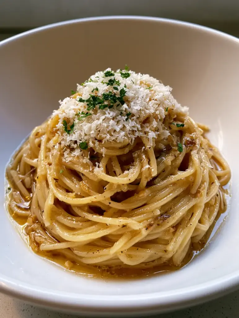 Close up of Garlic Butter Pasta topped with a thick layer of finely grated parmesan cheese and green parsley flakes.