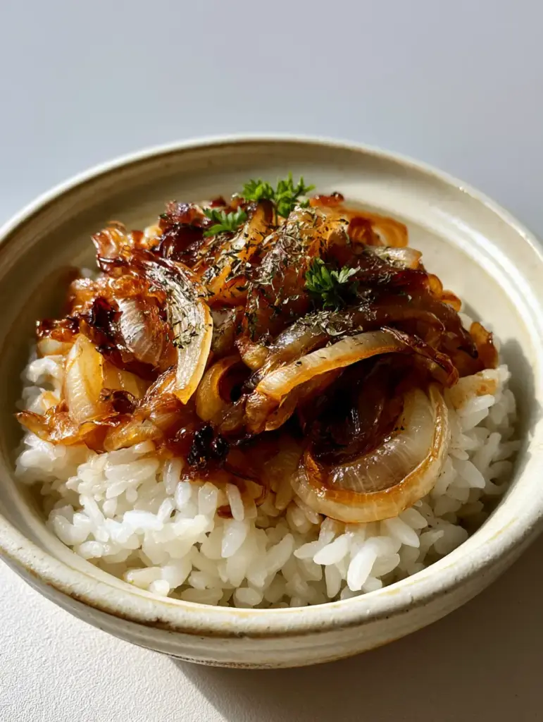Onion Rice Recipe with Caramelized Golden Onions 2 Close-up of steamed long-grain rice and charred onions in a light ceramic bowl. (Onion Rice Recipe)