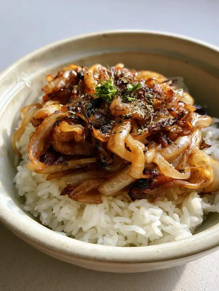 Onion Rice Recipe with Caramelized Golden Onions 1 A handheld smartphone photo of deep bronze onions over white rice on a grey surface.